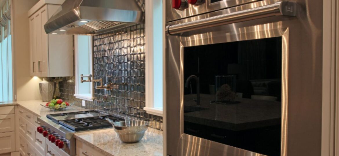 Luxury kitchen cabinets Longboat Key — white recessed panel cabinetry with Wolf wall oven, Wolf range, metallic tile backsplash, and granite countertops by EuroTech Cabinetry